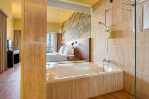 a bathroom with a bath tub and a bedroom at Calheta Beach - All-inclusive - Savoy Signature in Calheta