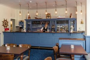 a man standing behind a bar in a restaurant at Kviknes Hotel in Balestrand