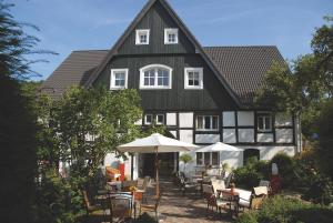 ein großes schwarzweißes Haus mit Tischen und Stühlen in der Unterkunft Romantik Hotel Neuhaus in Iserlohn