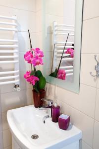 un lavabo con flores rosas en un jarrón. en Furmanska 3 Mansarda, en Leópolis