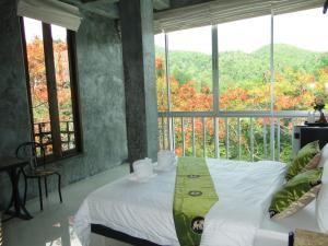 a bedroom with a bed and a large window at Hern Lhin Natural Resort in Ban Pong