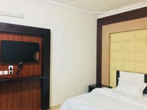 a bedroom with a bed and a flat screen tv at Kasr Dama Furnished Apartments in Ḑubā