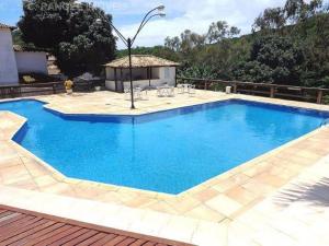 a large blue swimming pool with a wooden deck at Geriba, casa de 4 qts charmosa com ar, DISPONIVEL CARNAVAL in Búzios