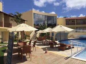 a patio with chairs and umbrellas next to a pool at Solar Agua in Pipa