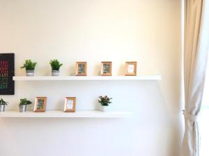 a white shelf with pictures and plants on it at KL Gateway Residency in Kuala Lumpur