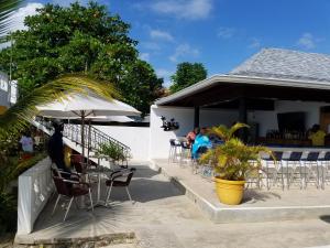 un patio con mesas y sillas y un bar en White Sands Negril, en Negril