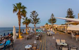 uma praia com mesas e cadeiras e o oceano em Dessole Malia Beach - All Inclusive em Malia