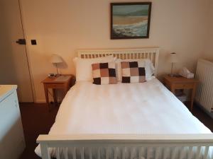 1 dormitorio con 1 cama blanca y 2 mesitas de noche en The Mill House en Tintagel