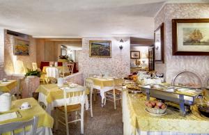 un comedor con mesas y sillas y una habitación con mesas y mesa en Colonna Palace Hotel Mediterraneo, en Olbia