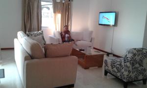 a woman and a child sitting in a living room at Jbillaselfcatering in Beau Vallon