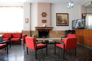 a waiting room with red chairs and a fireplace at Noufara Hotel in Kamena Vourla