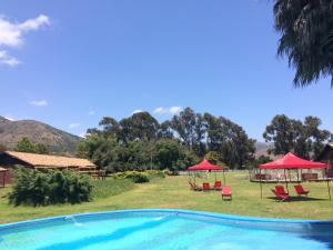 una piscina con ombrelloni e sedie rossi di Hotel Haras Casacampo a Quintero