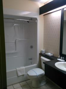 a white toilet sitting next to a bath tub in a bathroom at Days Inn by Wyndham Montmagny in Montmagny