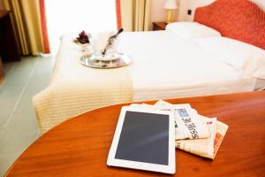 a cell phone sitting on top of a bed next to a book at Hotel Fontana Olente in Ferentino
