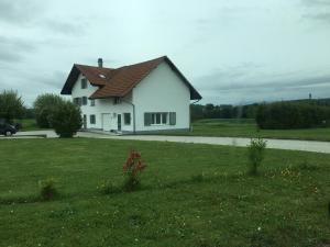 a white house with a brown roof on a grass field at Chambre d'hôtes du Guéravet in Grolley