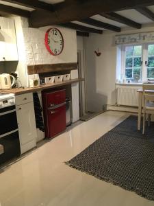 a kitchen with a red clock on the wall at The Cottage in Sulgrave