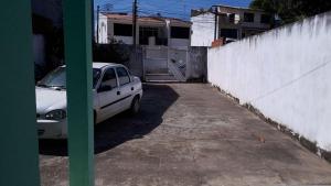 um carro branco estacionado numa garagem ao lado de uma cerca em Hospedagem Vovó Gina em Aracaju