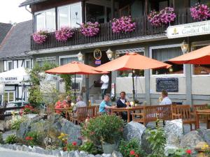 a group of people sitting at a restaurant with umbrellas at Gasthof Müller in Winterberg