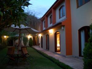 a house with a table and an umbrella in the yard at Hotel Meliana in Arequipa
