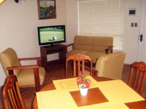 a living room with a table and a television at Apart Hotel en Puerto Montt in Puerto Montt