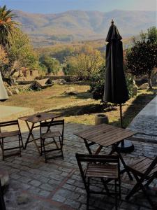 un patio con sombrilla, mesas y sillas en De Aldaca Rural - Only Adults, en Jerte