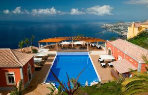 a house with a swimming pool and a view of the ocean at Designed Villa Palheiro Village by Holiday Rental Madeira in Funchal