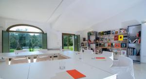 een kamer met witte tafels en stoelen en een boekenplank bij Acquaghiaccia Spa & Country House in Vagli