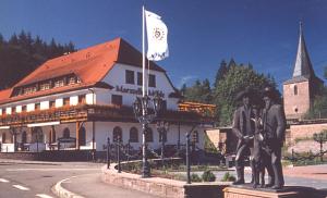 eine Statue vor einem Gebäude mit einer Flagge in der Unterkunft Hotel Marxzeller Mühle in Marxzell