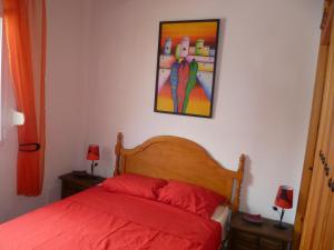 - une chambre avec un lit rouge et un tableau mural dans l'établissement Villa Competa, à Cómpeta