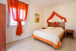 a bedroom with a bed and a window with red curtains at Antheon Villas in Chrysi Ammoudia