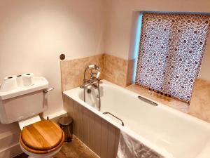a bathroom with a toilet and a bath tub at The Dorset Arms Pub & Cottage Rooms in Groombridge +41 photos