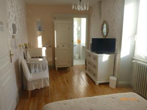 - une chambre avec une télévision et une commode avec une commode dans l'établissement LOGIS HOTEL Les Tilleuls, à Saint-Cirgues-de-Jordanne