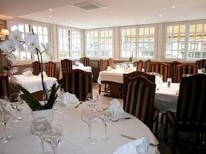 un comedor con mesas blancas y sillas con copas de vino en Auberge Du Cheval Blanc, en Crèvecoeur-en-Auge