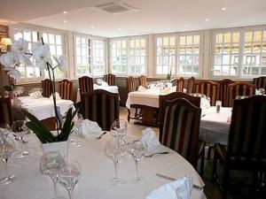 een eetkamer met witte tafels en stoelen met wijnglazen bij Auberge Du Cheval Blanc in Crèvecoeur-en-Auge