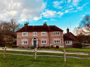 an old brick house with a fence in front of it at The Dorset Arms Pub & Cottage Rooms in Groombridge