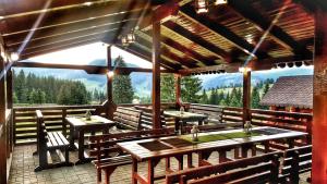 Un restaurante con mesas y bancos de madera en una terraza. en Casa Arini Bellevue, en Vatra Dornei