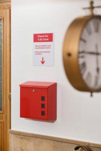 un reloj en una pared junto a una caja roja en Hotel Mille Stelle City, en Heidelberg