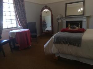 een slaapkamer met een bed, een tafel en een spiegel bij House On Plein in Paarl