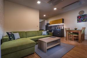 a living room with a green couch and a table at Apartmánový Dom Kriváň in Bešeňová