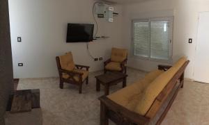 Una sala de estar con un sofá y sillas y un televisor. en La Casita de Thor, en Monte Hermoso