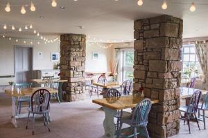 a restaurant with tables and chairs and a stone wall at Melvich Hotel in Portskerra