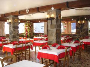 a dining room with red and white tables and a christmas tree at Hotel Le Parpaillon in Crévoux