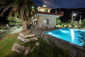 a villa with a swimming pool at night at Pericles Beach Villa in Kissamos