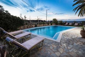 Pericles Beach Villa في كيساموس: مسبح يوجد بجانبه كرسيين جلوس