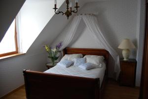 ein Schlafzimmer mit einem weißen Bett mit Baldachin in der Unterkunft La Roseraie in Ergué-Gabéric