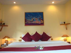 a bedroom with a large bed with red pillows at Palm Garden Resort in Rawai Beach