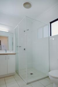 a white bathroom with a shower and a toilet at Artesian Spa Motel in Moree