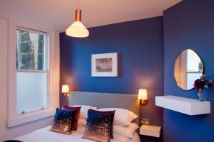 a bedroom with blue walls and a bed with pillows at MyCityHaven Boutique Luxury in Bath City Centre in Bath