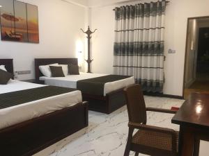 a hotel room with two beds and a table at Blue Wings Beach Hotel in Trincomalee