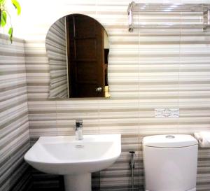 a bathroom with a sink and a toilet and a mirror at The Ambassador Hotel in Tacloban